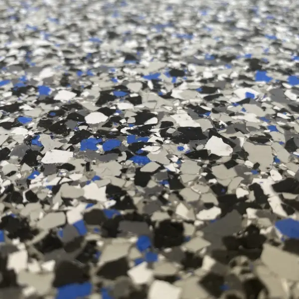 Speckled surface with gray, black, white, and blue chips. Textured pattern creates a visually engaging, abstract appearance captured in a close-up perspective.